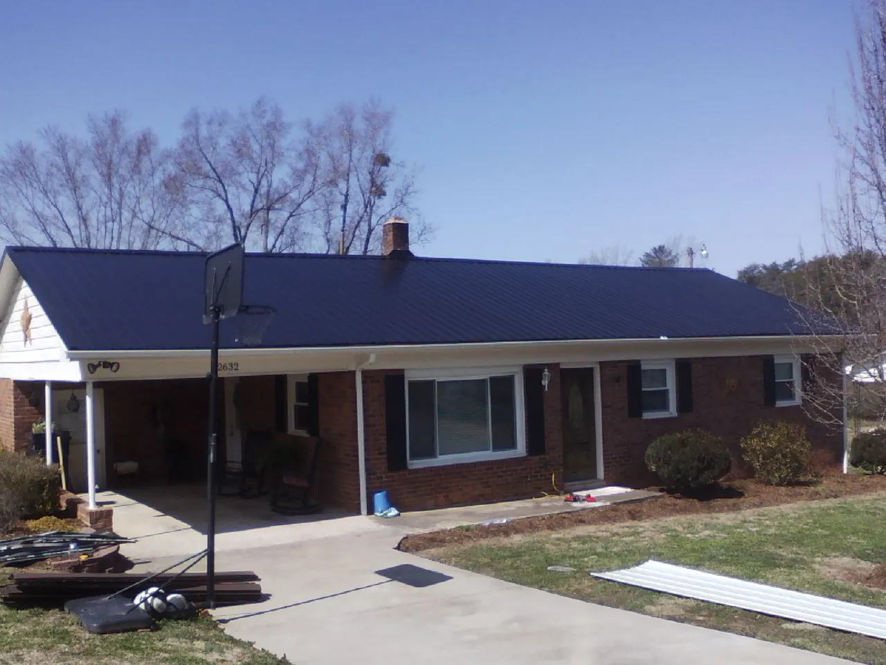 Finished dark blue metal roof on a brick ranch with a carport in Kingston